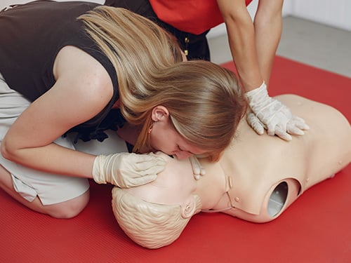 Woman performing CPR after a first aid course.