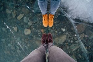 Two people standing on ice which is ready to break