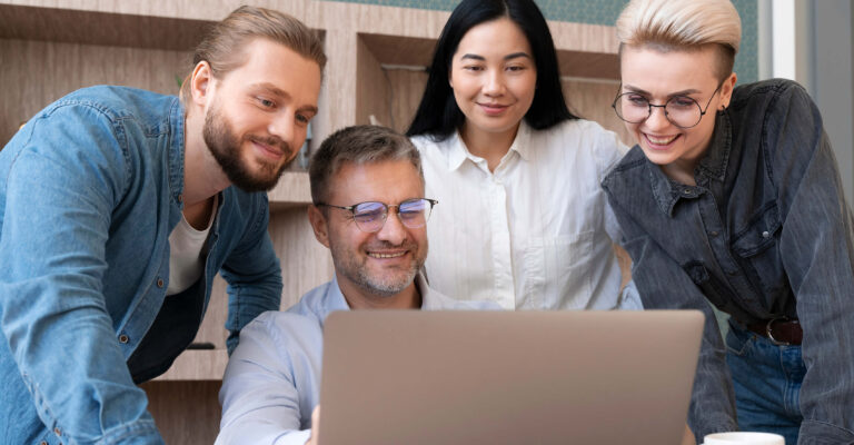 3B Team gathered round a laptop at work