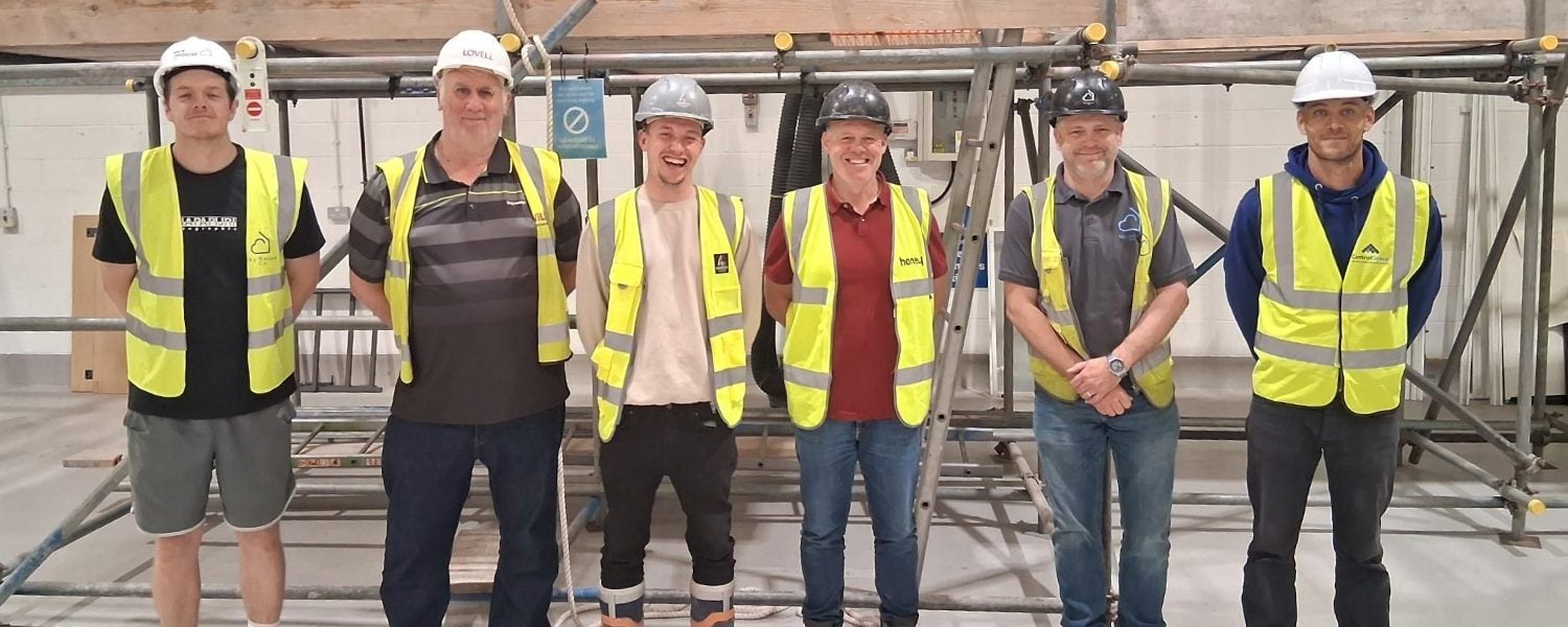 Five delegates stand in front of scaffolding