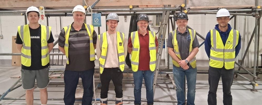 Five delegates stand in front of scaffolding