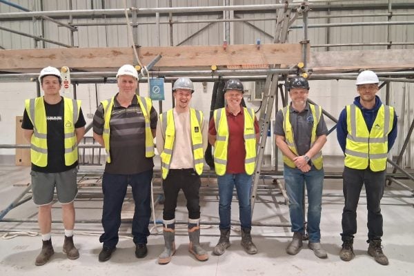 Five delegates in front of scaffolding smile for the camera