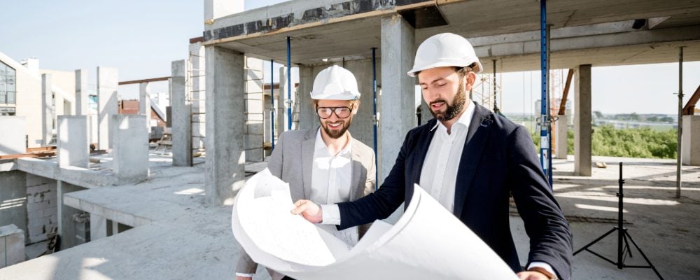 Two men review construction plans