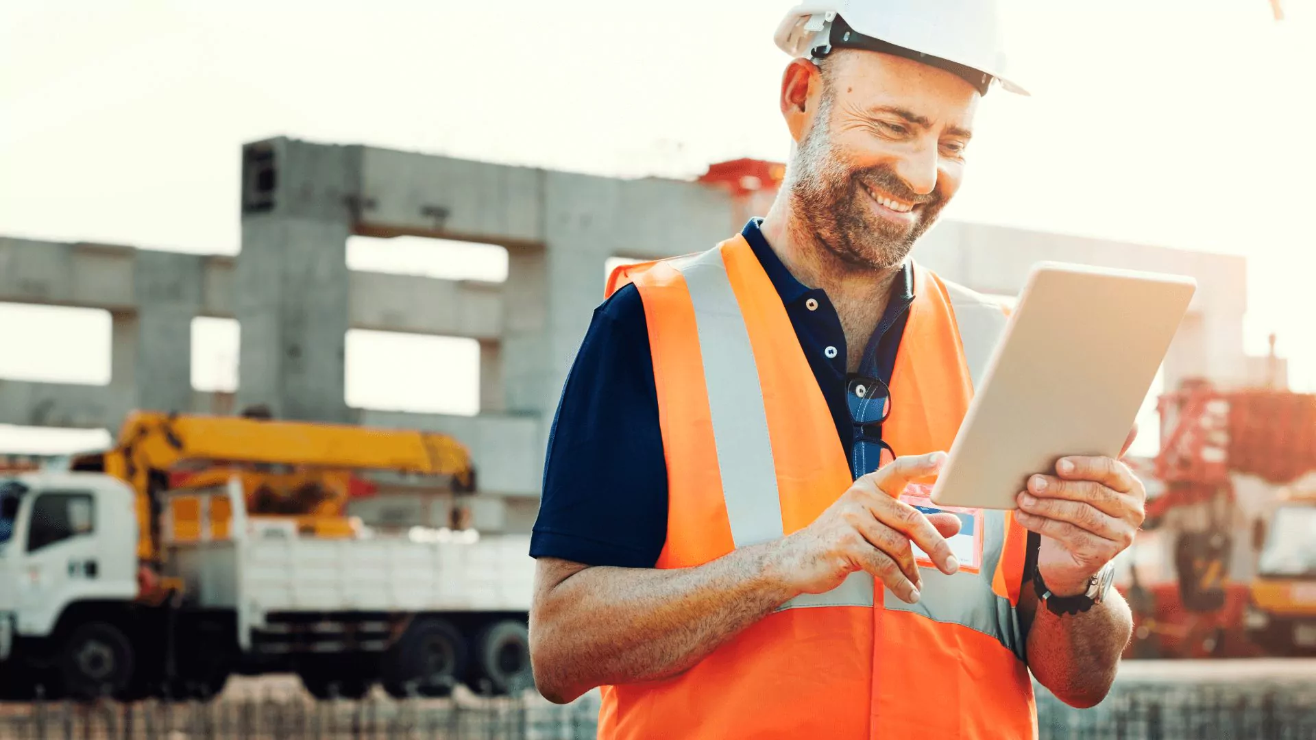Man smiles at tablet on construction site
